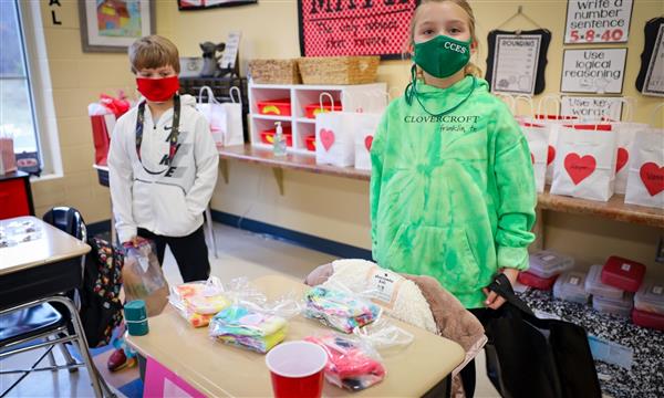 students stand next to desks during Market Day